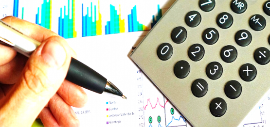 persons hand holding pen checking numbers using calculator